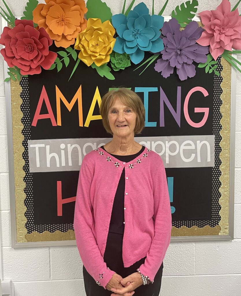 A woman is standing in front of a bulletin board.